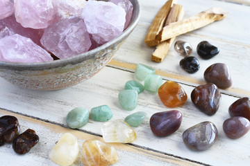 A top view image of rose quartz and various energy healing crystals on a white wooden table. 