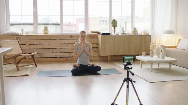 Attractive Caucasian female starting live stream or vlog about doing yoga at home. Stay home, quarantine workout. Shot on ARRI Alexa Mini with Cooke S4 lenses
