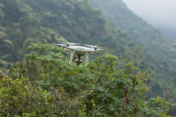 White drone with camera flying in spring mountains