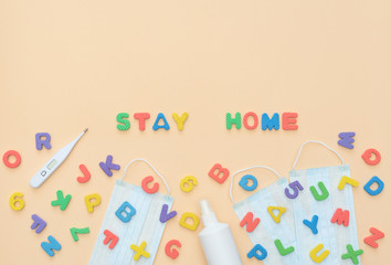 Multi-colored soft English letters and numbers lie on medical face masks with thermometer and sanitizer on yellow background. Kid's set for teaching reading, counting. Home schooling concept.