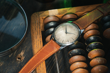 Vintage watch with brown leather strap, lying between different vintage stuff.