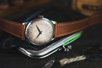 Vintage watch with brown leather strap, lying between different vintage stuff.