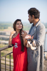 An young Indian brunette couple in western dress enjoying themselves on the rooftop in urban background in home quarantine. Indian lifestyle.
