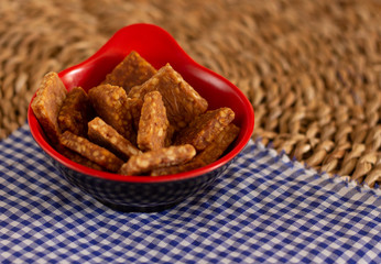 small bowl with delicious peanuts with a straw background