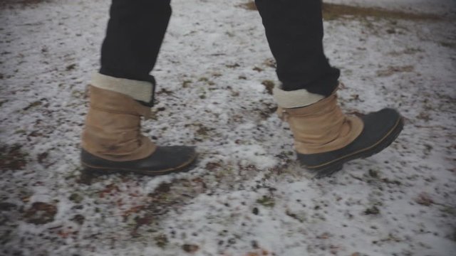 A Person Wearing A Black And Brown Ankle Boots Used For Walking In Dirt Road. -close up shot