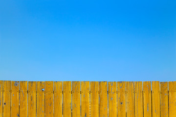 青空と黄色の古びた板塀。背景用素材