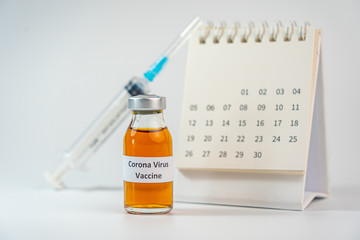 Coronavirus vaccine bottle and syringe injection next to 2020 calendar 
