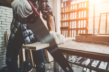 Carpenter working on wood craft at workshop to produce construction material or wooden furniture. The young Asian carpenter use professional tools for crafting. DIY maker and carpentry work concept.