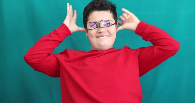 Portrait of a happy cute teenage boy making funny grimace gainst chroma key green screen background