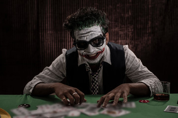 Portrait of an Indian man in Halloween costume showing scary facial expression in front of a casino poker table. Cosplay photography. - obrazy, fototapety, plakaty