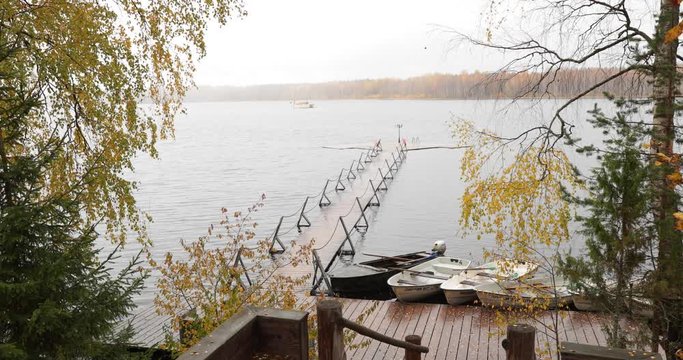 The Long pier on the lake, Terrace at the lake, the Autumn at the lake Boroye, Boats at a pier, Valday national park, Russia, panoramic image, golden trees, Wooden lodges, cloudy weather