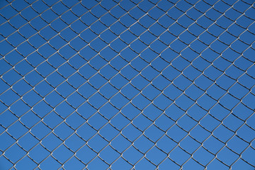 Steel mesh wire fence with blue sky under blue sky.