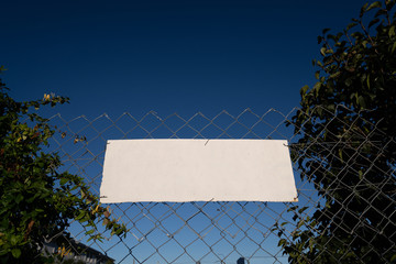 Empty white sign on  fence offers copy space.