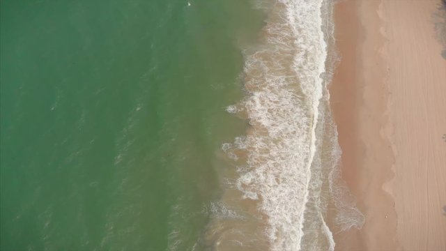 Aerial shot Aerial view of the drone from the ocean, ocean waves, beautiful waves do not end frames one by one while the turquoise sea waves break on the sandy coast. 4K