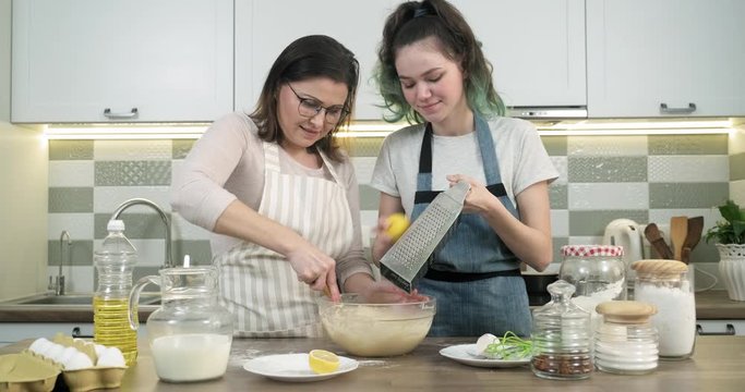 Mother with teenage daughter cooking together in kitchen