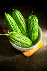Fresh bitter melon or pare on white bowl. healty vegetable with contains many nutrients that are good for the body. dark background