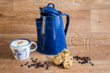 Blue coffee-pot, cup of coffe and rusks on a wooden table.