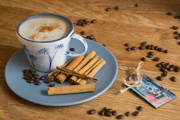 Cup of coffee with cinnamon sticks on a wooden table