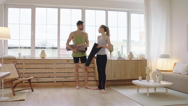 Fit young adult Caucasian couple living together practicing yoga at home. Girlfriend teaching boyfriend how to do yoga. Stay home, quarantine workout. Shot on ARRI Alexa Mini
