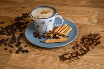 Coffee, cinnamon sticks and roast coffee beans in a blue plate on a wooden table.