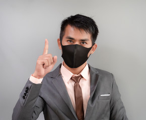 Asian businessman is wearing mask trying to protect from coronavirus or covid 19 epidemic over gray background.