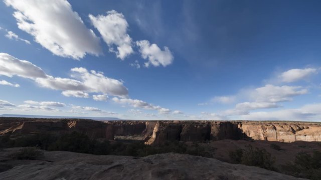 An ultrawide timelapse of Canyon De Chelly as clouds flow overhead on a winter afternoon casting shadows on the canyon walls and valley floor.
