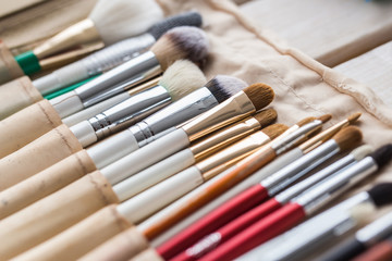 Fototapeta premium Makeup, beauty and cosmetics concept - Set of make-up brushes in a light case.