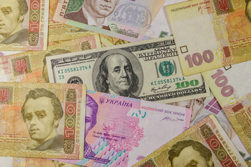One hundred dollar bill on a background of different ukrainian hryvnia banknotes