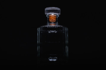 Empty bottle of whiskey on the black background.