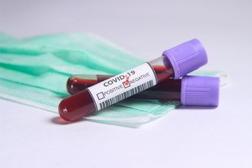 Close Up Photo, Simple Conceptual, Glass Blood Covid-19 Test tube, negative result, above N95 Surgical Mask
