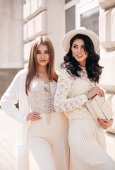 beautiful girls with dark hair in elegant clothes posing in the street