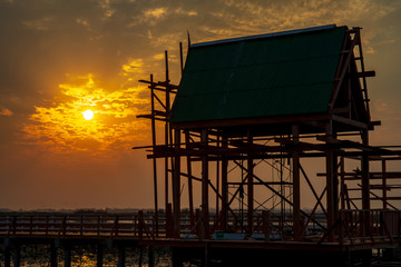 Vintage Wooden Pavilion is under construction with light from sunset or evening time at water lake...