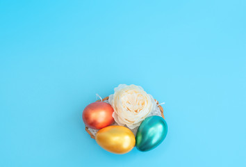 Decorated Easter eggs lie in the basket like a nest with white flower on blue background. Happy...