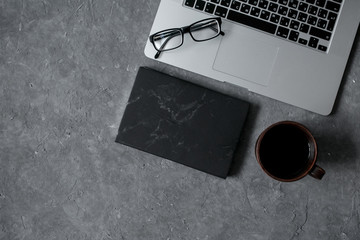 smartphone on office desk with laptop and cup of coffee on gray concrete. Business or education concept. Top view with copy space, flat lay.
