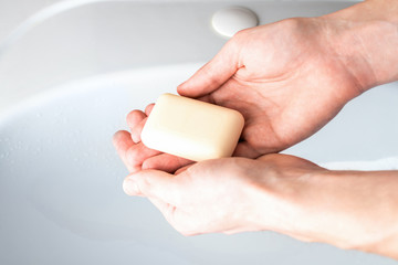 Soap in the hands of a man against the background of the sink in the bathroom. Hygiene concept for...