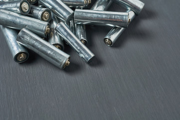 Heap of old dirty batteries aa or aaa size on dark concrete desk. Recycling concept. Save environment. Alternative energy