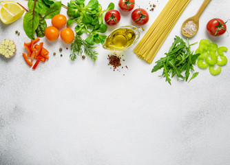 Fresh raw ingredients for vegetarian salad or pasta sauce and raw spaghetti on light background.Top view,copy space.
