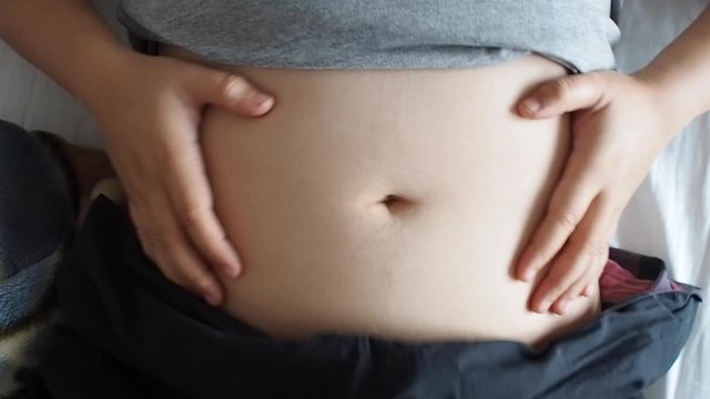 Woman is so funny and enjoy beating her big belly with rhythm while her lay down watching  Movie or playing with her baby in pregnant 