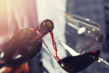 Waiter sommelier pouring red wine in glass - obrazy, fototapety, plakaty
