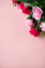 A bouquet of roses lies on a pink background a banner, a place for text, a romantic concert for Valentine's day, top view, vertical