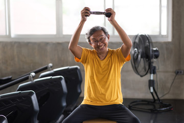 Happy old man  exercise dumbbell in gym