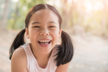 sweet little girl outdoors in the wind. portrait of attractive little student girl with beautiful. happy smiling child looking at camera - close-up, outdoors. jolly nature childhood leisure concept.