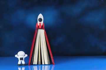 concept of success with toy rocket in the sky and astronaut and a book or diary as launching platform. Cosmonautics Day. Creativity and thinking outside the box, growth and development. Copy space