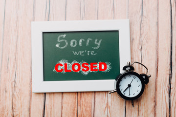 Sign "Sorry, we are closed" on a chalk board with English inscriptions on a wooden