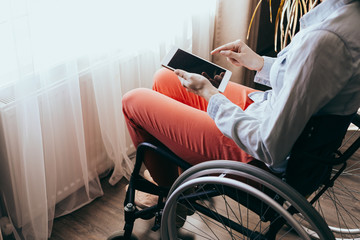 Fototapeta na wymiar unrecognizable young disabled woman in a wheelchair with a modern tablet.