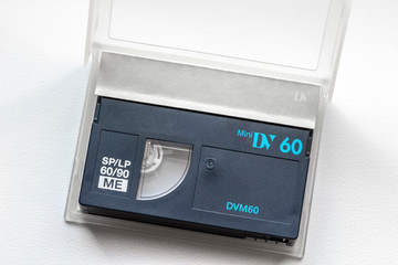 Old mini DV cassette in an open case on a white windowsill.