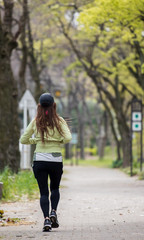 春の公園でジョギングしている若い女性