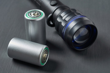 Old batteries near flashlight on dark concrete desk. Survival, tourism concept