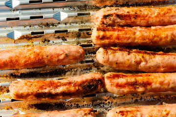 Sausages meat grilling on gas grill