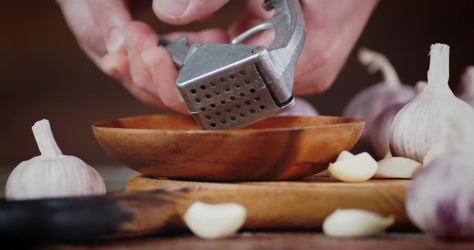 Man's hands crushed a garlic in masher.